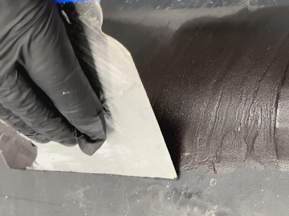 Lo stucco per riparazione della plastica colore nero si stende facilmente sulle superfici in plastica con una spatola